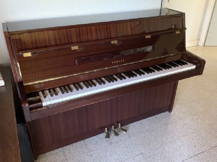 Piano droit Yamaha en bois verni 88 touches et trois pédales à accorder.